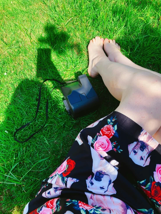 a woman laying on top of a lush green field, an album cover, inspired by Konstantin Somov, unsplash, happening, camera close to the legs, park on a bright sunny day, photo taken with an iphone, black cat at her feet