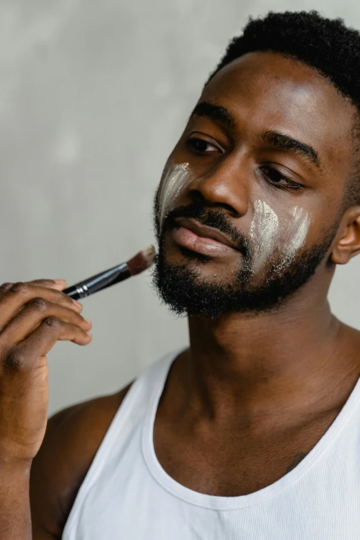 a man is shaving his face with a brush, by Cosmo Alexander, trending on pexels, hyperrealism, brown skin. light makeup, black chalk, thumbnail, white facepaint