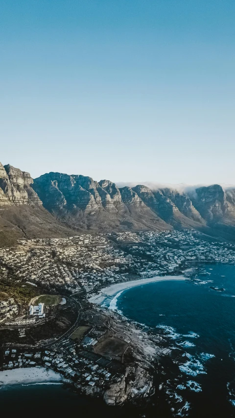 a large body of water surrounded by mountains, by Daniel Lieske, trending on unsplash, south african coast, aerial view of a city, high-quality photo, 8 k smooth