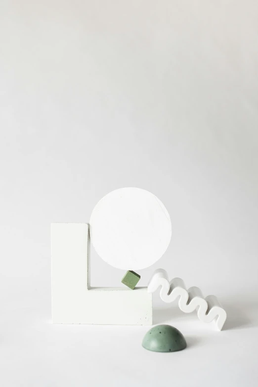 a mirror sitting on top of a white table, an abstract sculpture, by Leo Leuppi, professional product photo, green and white, art toy, kano)