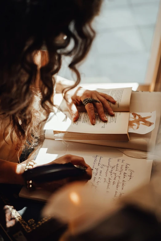 a woman sitting at a table reading a book, pexels contest winner, romanticism, with some hand written letters, thumbnail, reading for a party, curled up on a book