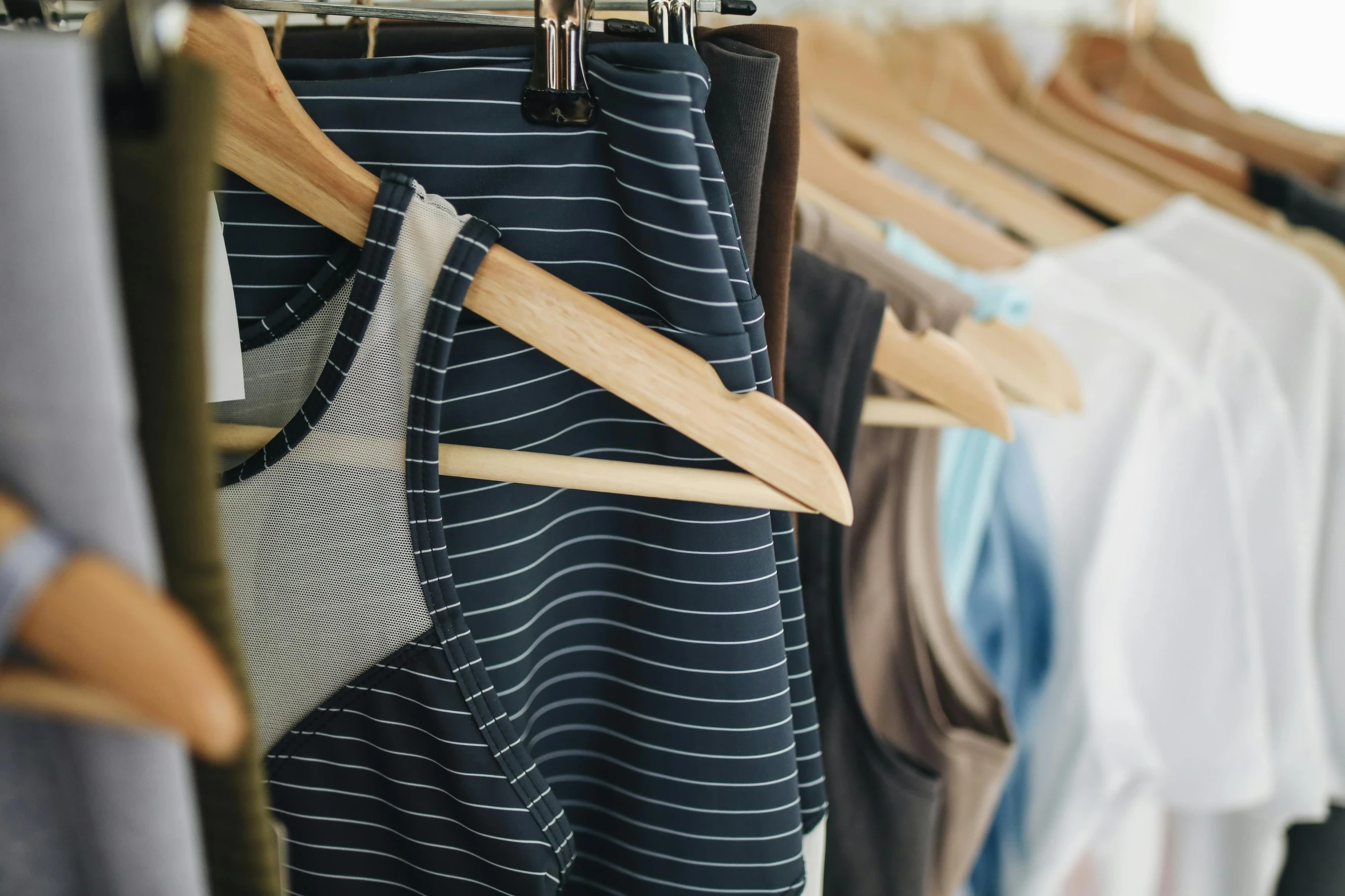 clothes hanging on a rack in a clothing store, by Carey Morris, trending on unsplash, sport bra and dark blue shorts, striped, wearing : tanktop, sustainable materials