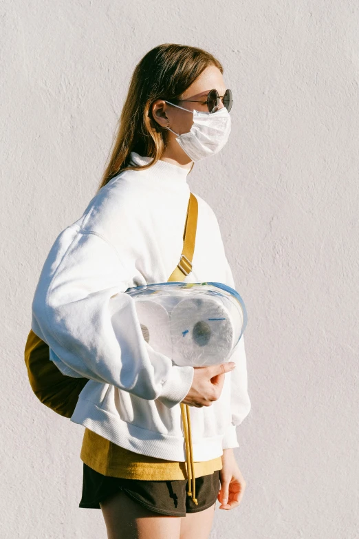 a woman wearing a face mask and carrying a bag, trending on pexels, visual art, wearing a white sweater, translucent body, mustard, holding a stuff