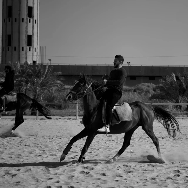 a man riding on the back of a brown horse, a black and white photo, pexels contest winner, arabesque, ameera al-taweel, riyahd cassiem, training, in an urban setting