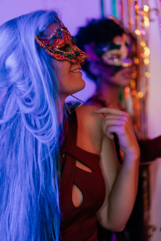 a couple of women standing next to each other, trending on pexels, renaissance, blue lights and purple lights, masked person in corner, party people in background, rich colourful