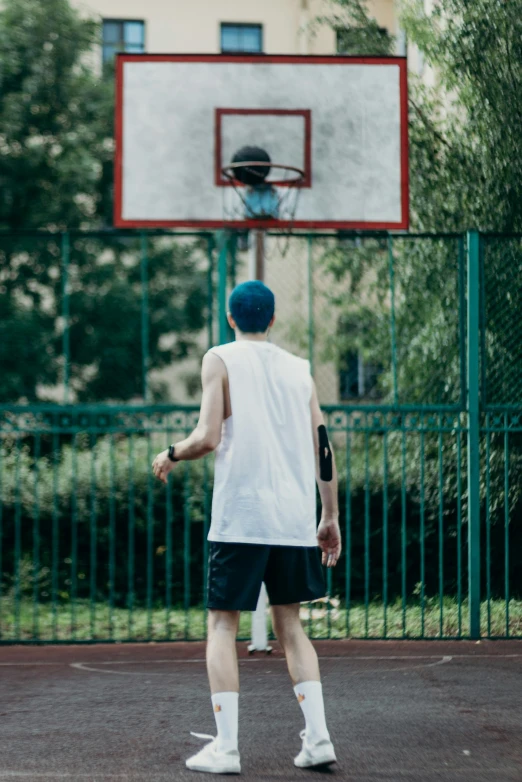 a man standing in front of a basketball hoop, by Adam Marczyński, trending on dribble, sport shorts, aged 13, in the park, back - shot