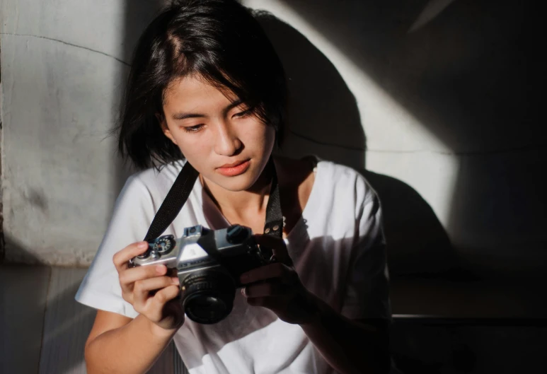 a close up of a person holding a camera, a picture, inspired by Vivian Maier, pexels contest winner, young asian woman, focused light, medium format, photo in color