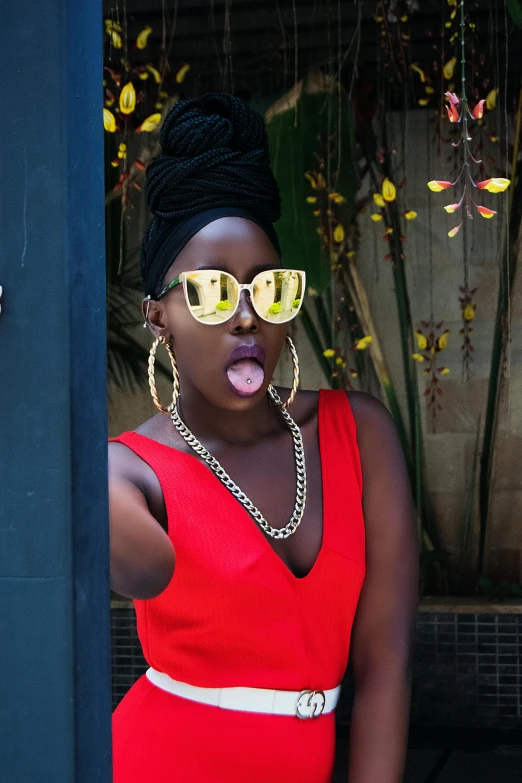 a woman in a red dress is sticking out her tongue, trending on unsplash, afrofuturism, gold glasses, very kenyan, black in, shaven