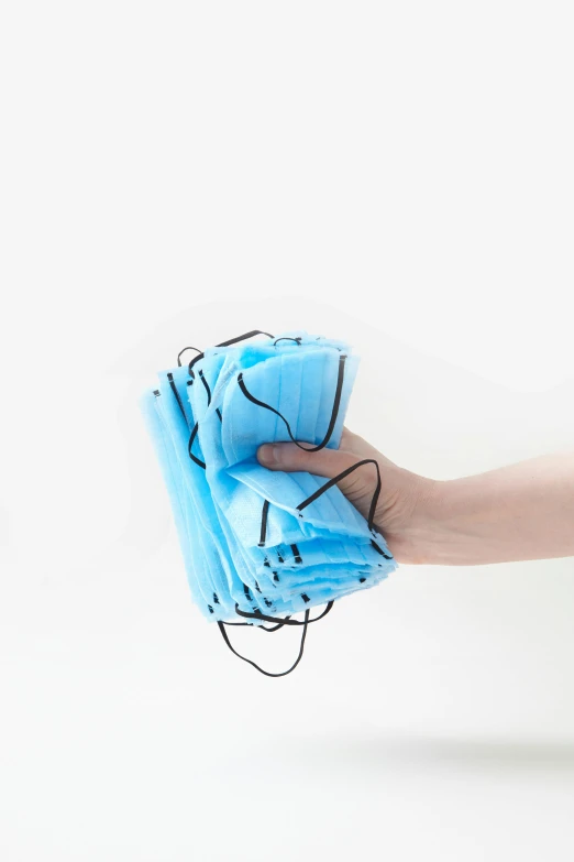 a person holding a blue object in their hand, face mask, masks on wires, with a white background, ((blue))