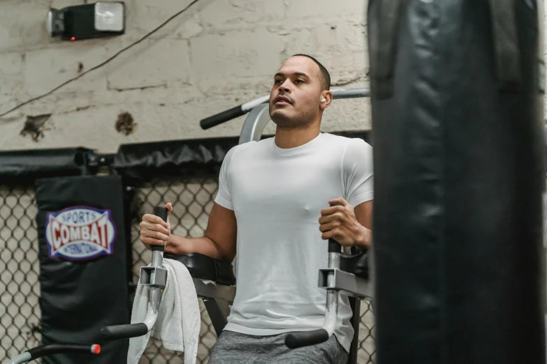 a man standing next to a punching bag, wearing a muscle tee shirt, sitting down, ronaldo nazario, background image