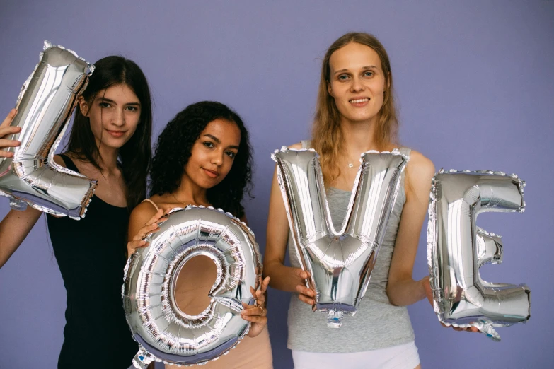 three women holding up silver balloons that spell love, by Olivia Peguero, trending on unsplash, lyco art, lovingly looking at camera, inflatable, avatar image, graduation photo