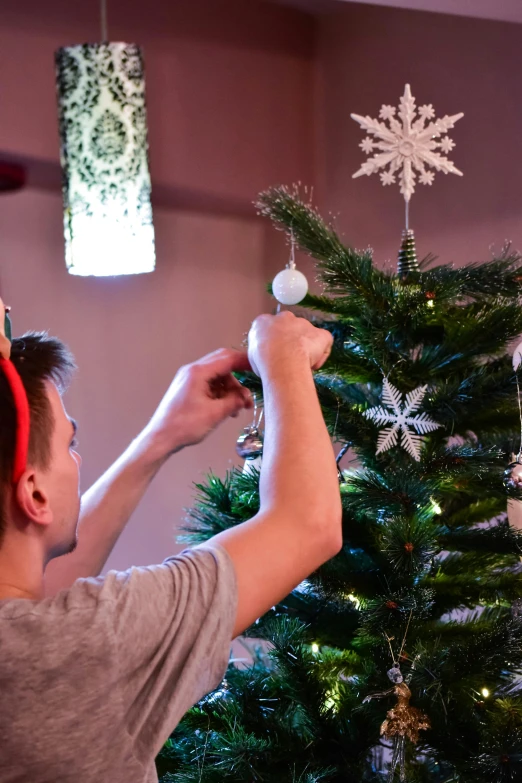 a man decorating a christmas tree with snowflakes, pexels, happening, teen elf, ornament crown, fully decorated, julian ope