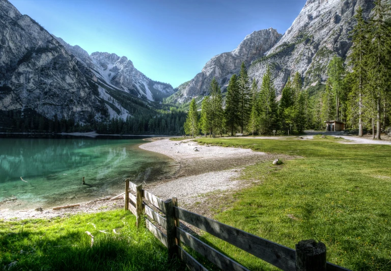 a wooden fence sitting next to a body of water, by Sebastian Spreng, pexels contest winner, hurufiyya, lago di sorapis, lawn, evergreen valley, youtube thumbnail