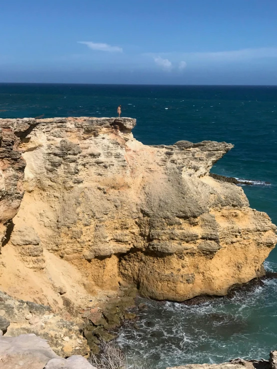 a man standing on top of a cliff next to the ocean, puerto rico, epic land formations, gigapixel photo, rock wall