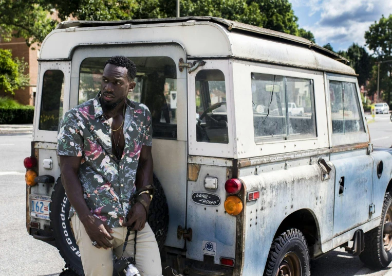 a man sitting on the back of a truck, an album cover, pexels contest winner, lupita nyong'o, land rover defender, jamaica, photograph 3 5 mm