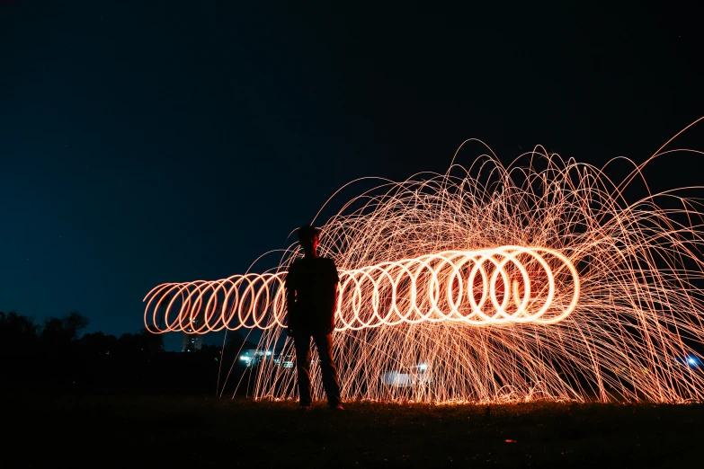 a person standing in front of a fire, a stipple, pexels contest winner, light trails, spiralling, ringflash, the pyro