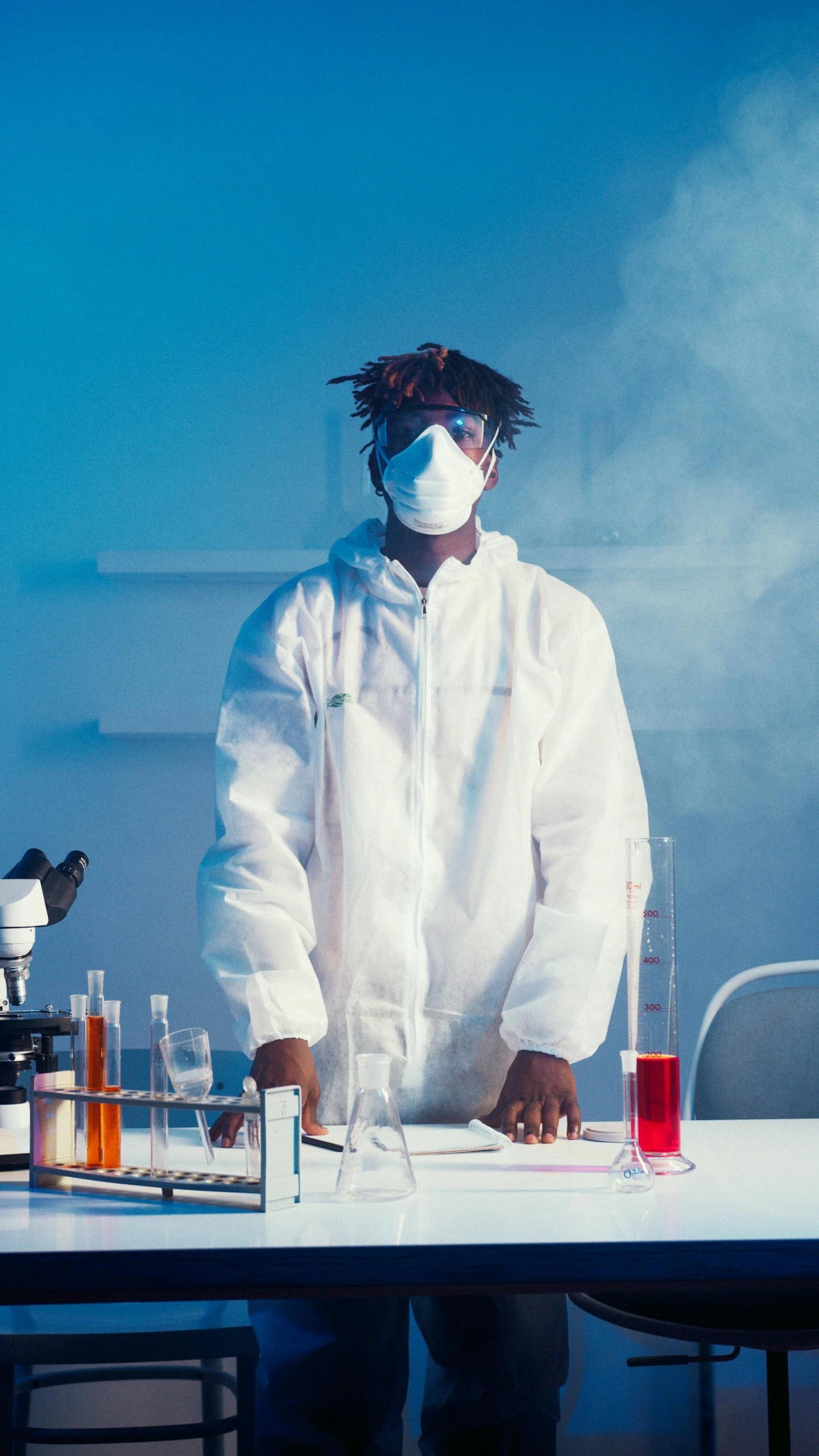 a man in a lab coat standing in front of a microscope, an album cover, trending on pexels, afrofuturism, medical mask, xxxtentacion, dry ice, photo shoot