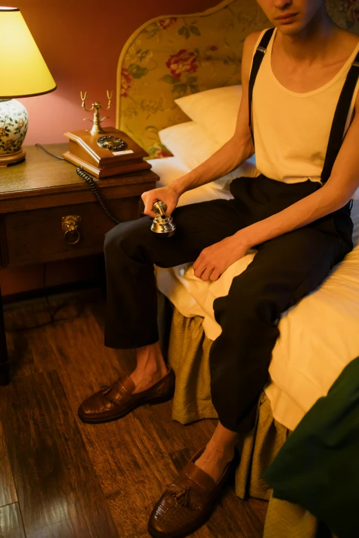 a woman sitting on top of a bed next to a lamp, inspired by Nan Goldin, trending on pexels, happening, subject detail: wearing a suit, suspenders, historically accurate, high angle