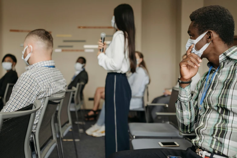 a man sitting in a chair talking on a cell phone, a cartoon, trending on pexels, standing in class, people are wearing masks, sitting in front of a microphone, group of people