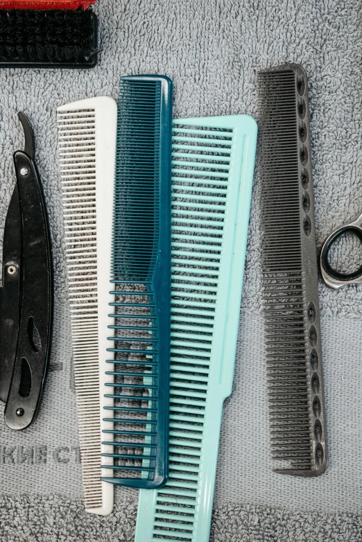 a variety of combs and scissors laid out on a towel, by Jason Felix, close - up profile, steel blades, shades of blue and grey, by greg rutkowski