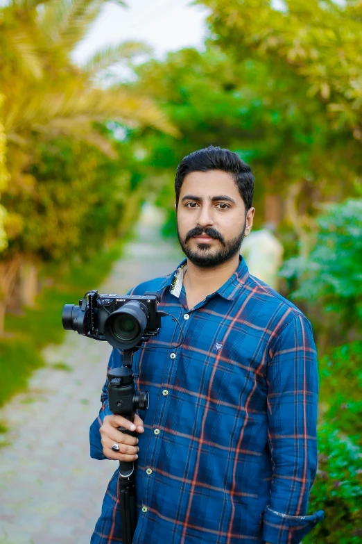 a man standing on a path holding a camera, by Riza Abbasi, halfbody headshot, 8k quality, video, home photography portrait