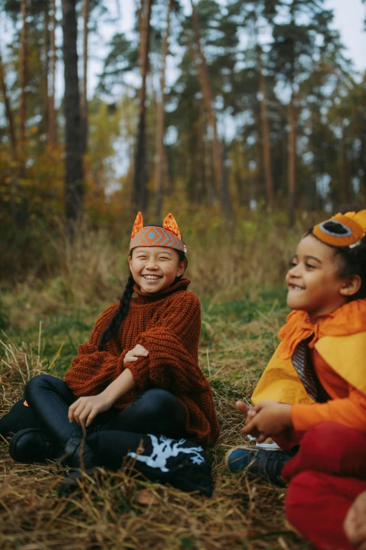 a group of children sitting on top of a grass covered field, in a forest, orange hoodie, laughing, girl with fox ears