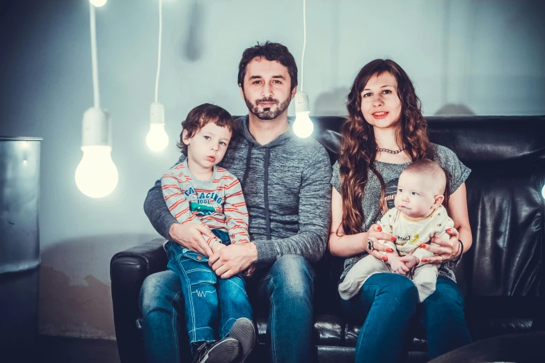 a man and woman sitting on a couch with a baby, a portrait, by Adam Marczyński, pexels contest winner, flashing lights, promotional image, group photo, hipster dad