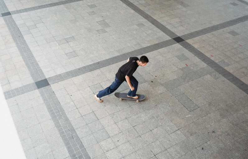 a young man riding a skateboard down a sidewalk, inspired by Fei Danxu, square lines, birdseye view, cinematic shot ar 9:16 -n 6 -g, ground - level medium shot