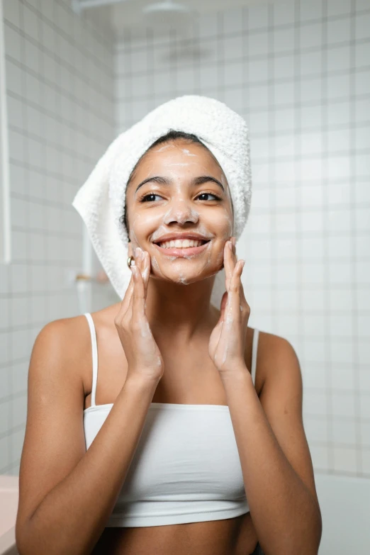a woman standing in a bathroom with a towel on her head, trending on pexels, renaissance, square facial structure, happy girl, silicone skin, olive skinned