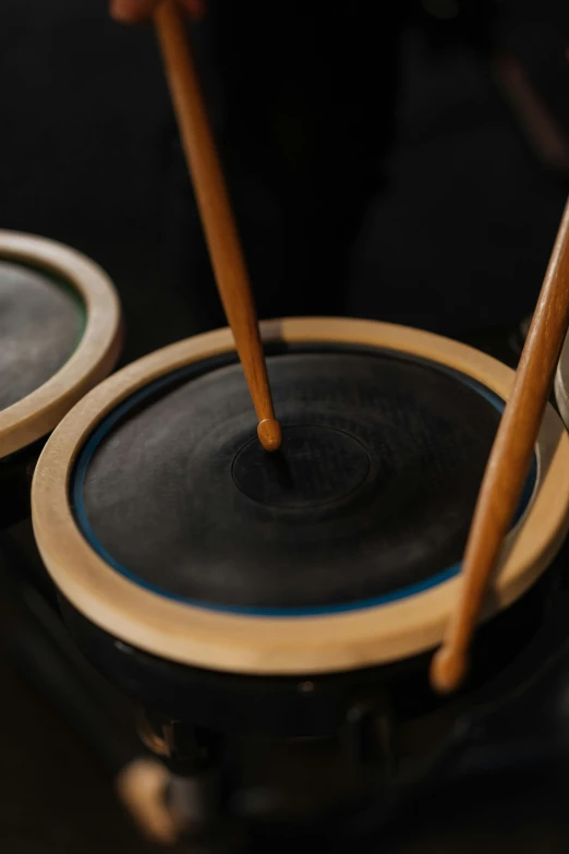 a couple of drums sitting on top of a table, inspired by Gong Kai, trending on unsplash, kinetic art, closeup - view, made of smooth black goo, made of bamboo, medium detail