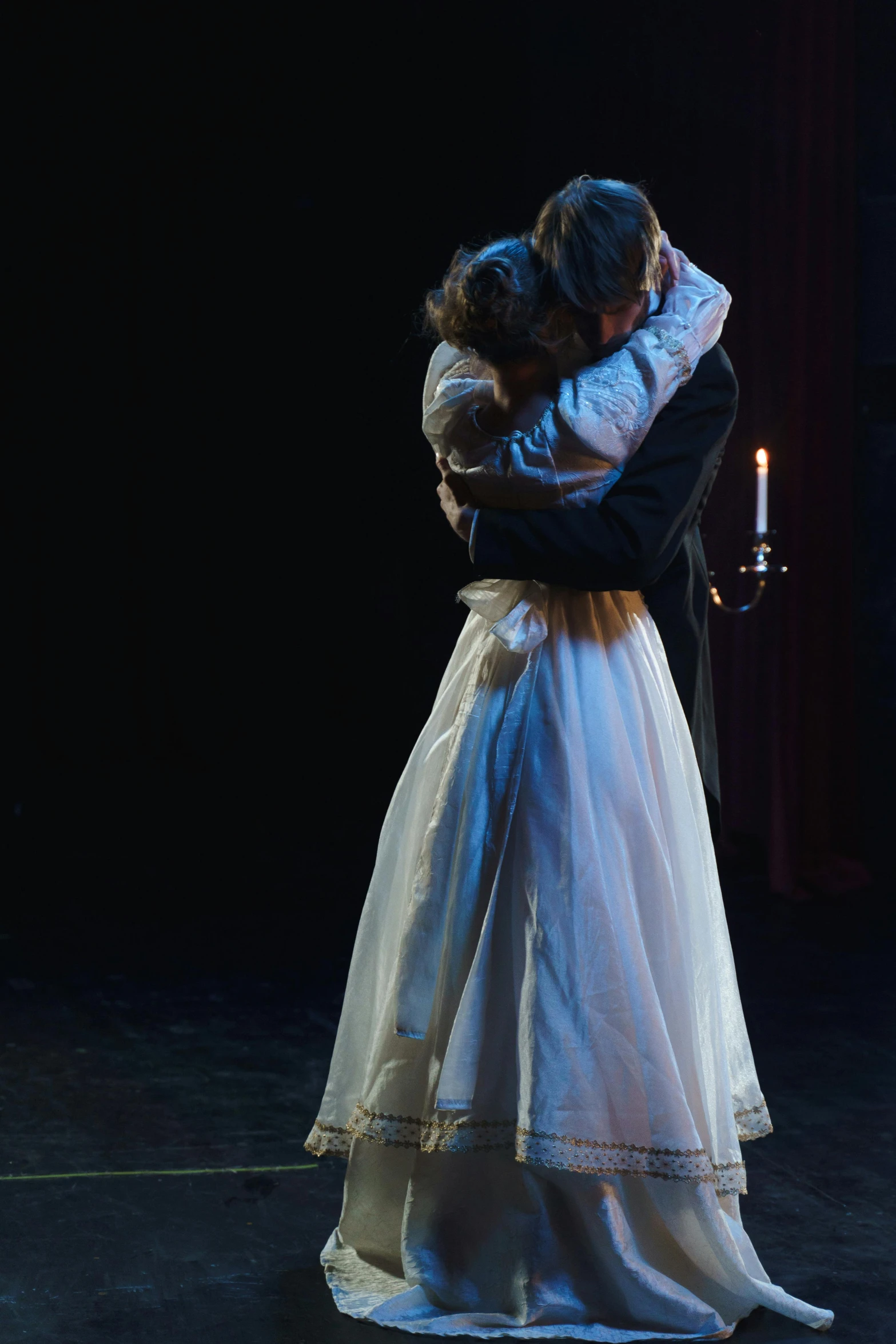 a couple of people standing next to each other on a stage, romanticism, embracing, production still, candlelit, b - roll