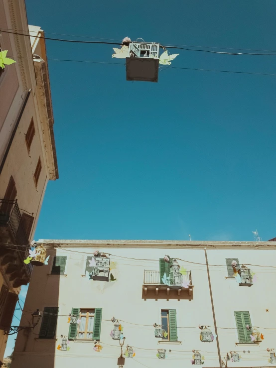 a couple of buildings that are next to each other, a picture, by Alexis Grimou, happening, light blue sky, things hanging from ceiling, in town, exterior photo