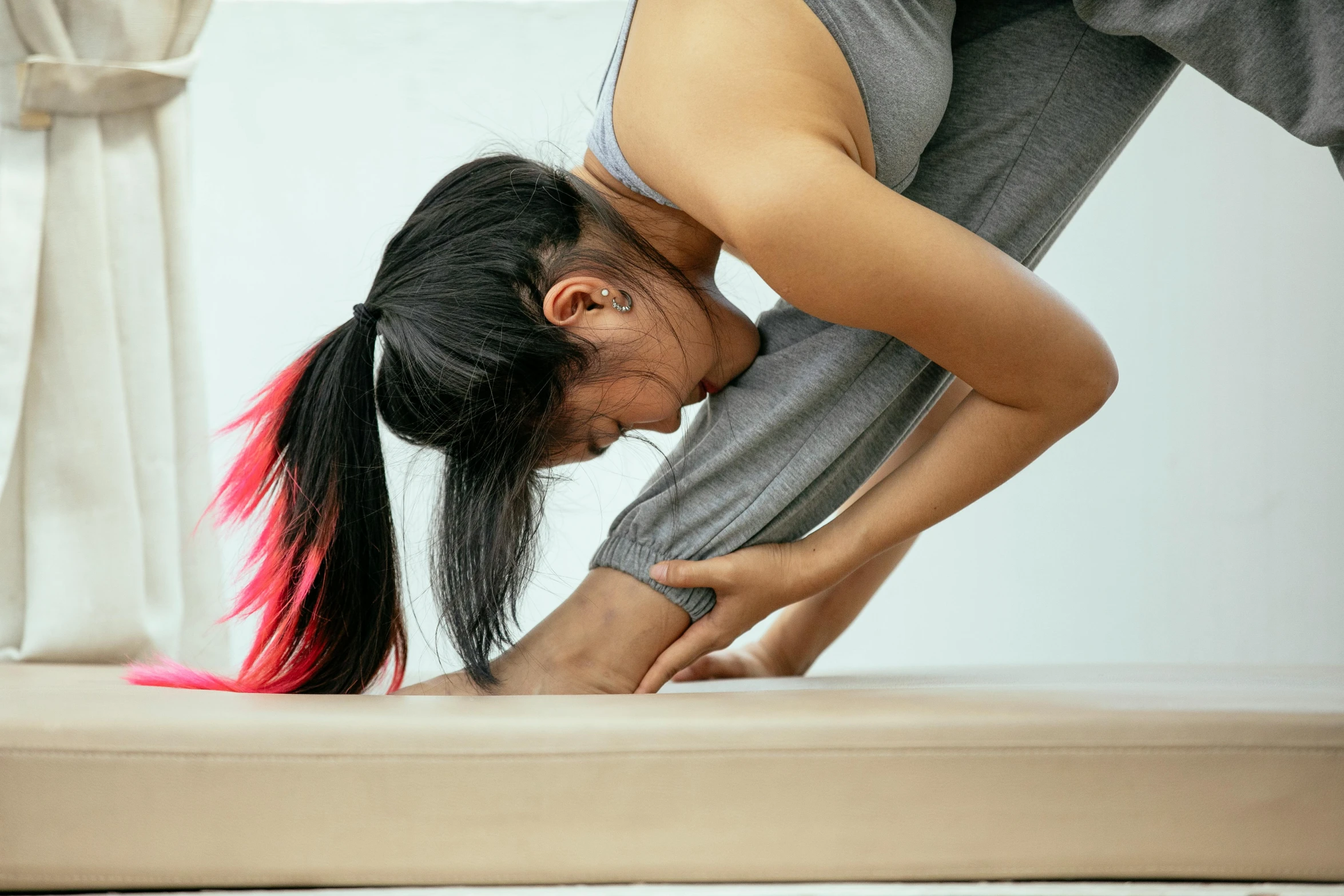 a woman doing a yoga pose on a mat, by Rachel Reckitt, trending on pexels, arabesque, close up shot from the side, contorted, asian female, looking from shoulder