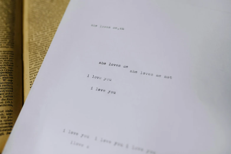 a piece of paper sitting on top of an open book, by Sylvia Wishart, unsplash, ascii art, i love you, on set, film stills, on a white table