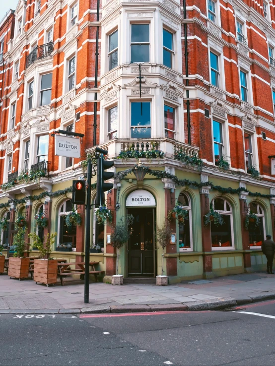 a tall red brick building sitting on the corner of a street, by Anna Findlay, unsplash, art nouveau, buying beers in the british bar, sage green, panorama shot, 😭 🤮 💕 🎀