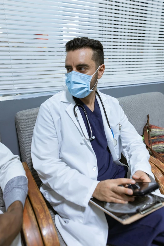 a couple of men sitting next to each other on a couch, masked doctors, looking at his phone, game ready, male physician