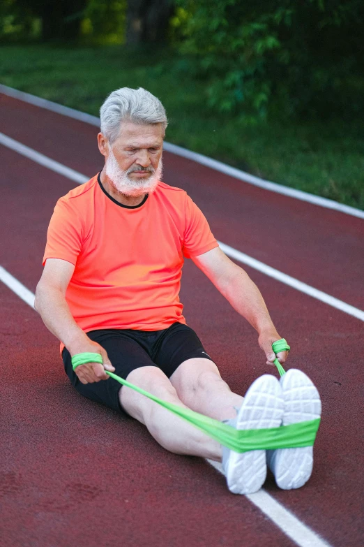 a man in an orange shirt is sitting on a track, older male, bendover posture, wearing fitness gear, square