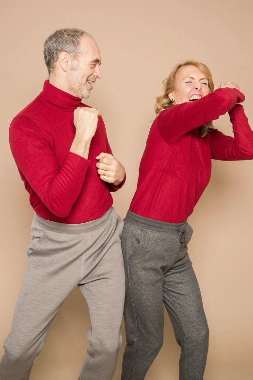 a man and a woman standing next to each other, by Nina Hamnett, trending on pexels, antipodeans, red sweater and gray pants, playful pose, fighting posture, mid thirties