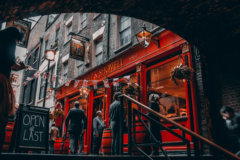a group of people standing outside of a building, by Julia Pishtar, pexels contest winner, buying beers in the british bar, cavern, red and black color scheme, ivy's