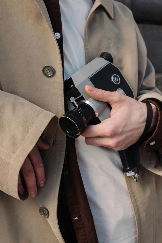 a man in a trench coat holding a camera, by Sven Erixson, unsplash, photorealism, william eggleston style, hasselblad medium format, animation, 268435456k film