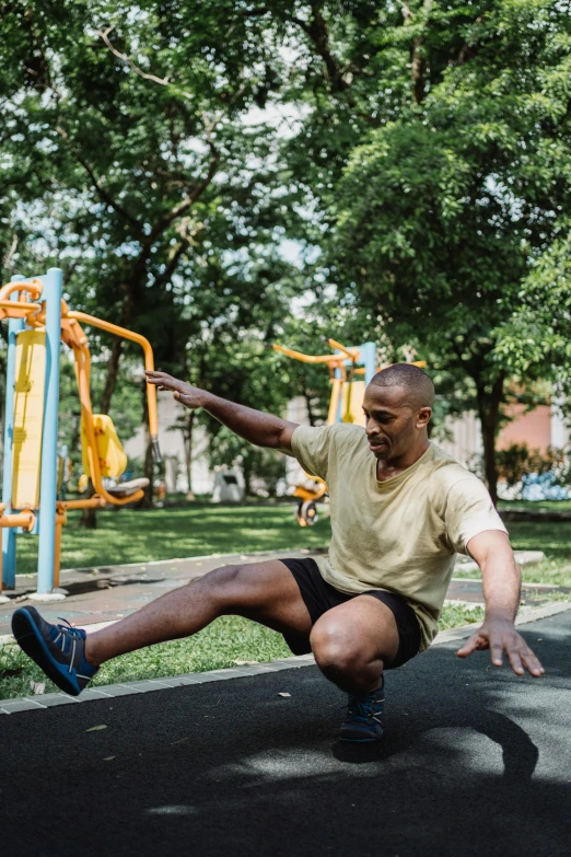 a man is doing a trick on a playground, by William Berra, pexels contest winner, muscular thighs, jemal shabazz, in a city park, shady