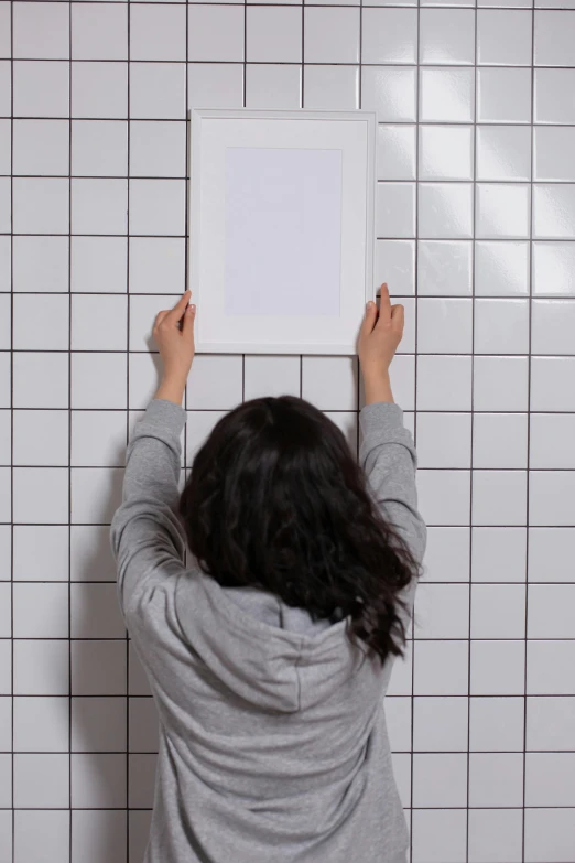 a woman standing in front of a white tile wall, a poster, trending on unsplash, conceptual art, hanging upside down, square, in bathroom, face down