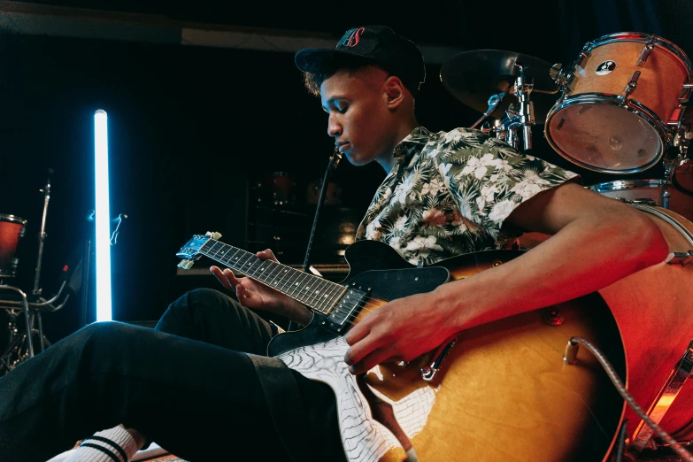 a man that is sitting down with a guitar, ashteroth, playing electric guitar, lachlan bailey, official store photo