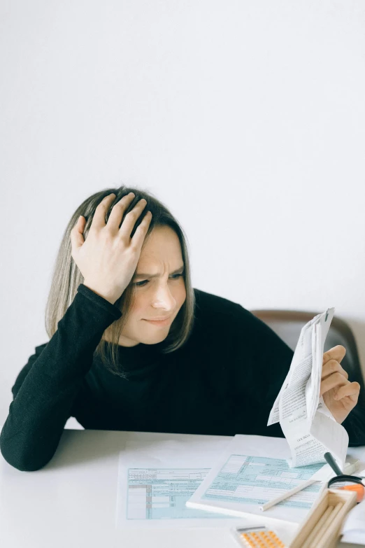 a woman sitting at a table with her head in her hands, trending on reddit, scratching head, papers, with a hurt expression, thinning hair