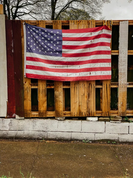 a fire hydrant in front of a fence with an american flag on it, pexels contest winner, outside a saloon, reclaimed lumber, profile image, boarded up