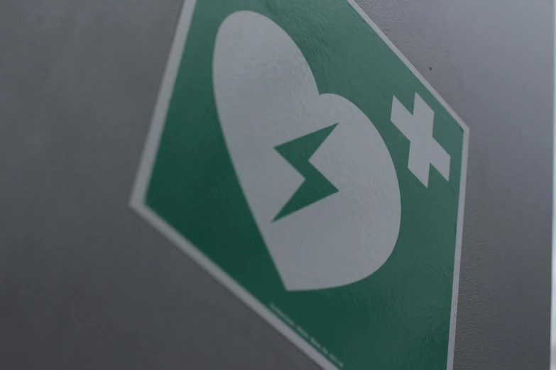 a close up of a green and white emergency sign, a poster, by Adam Marczyński, pexels, hearts, charging plug in the chest, square sticker, eu