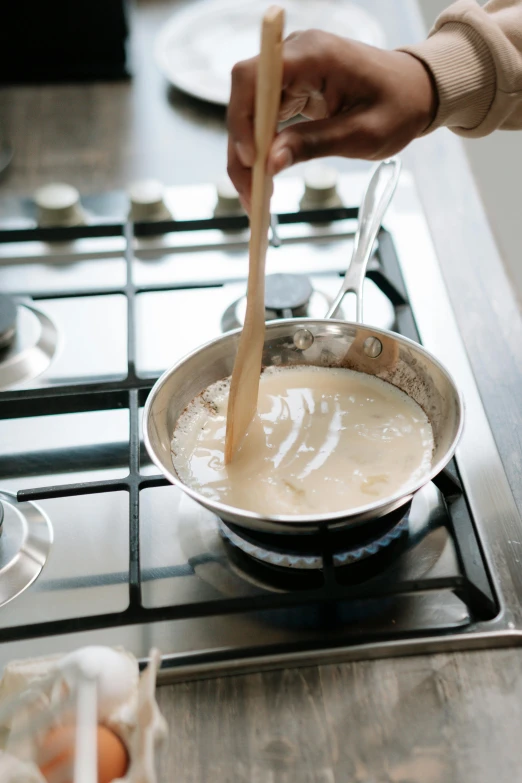 a person stirring something in a pan on a stove, cream, thumbnail, 4l, tall