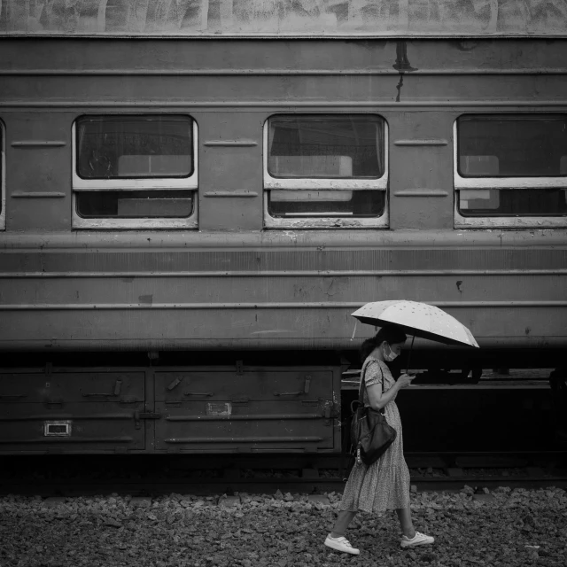 a woman with an umbrella walking in front of a train, a black and white photo, pyongyang, fan favorite, gray, 2 people