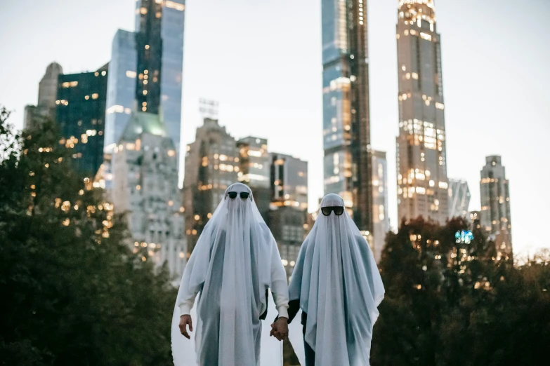 two people dressed in white standing next to each other, by Ellen Gallagher, pexels contest winner, halloween theme, new york city as backdrop, invisible man, ☁🌪🌙👩🏾