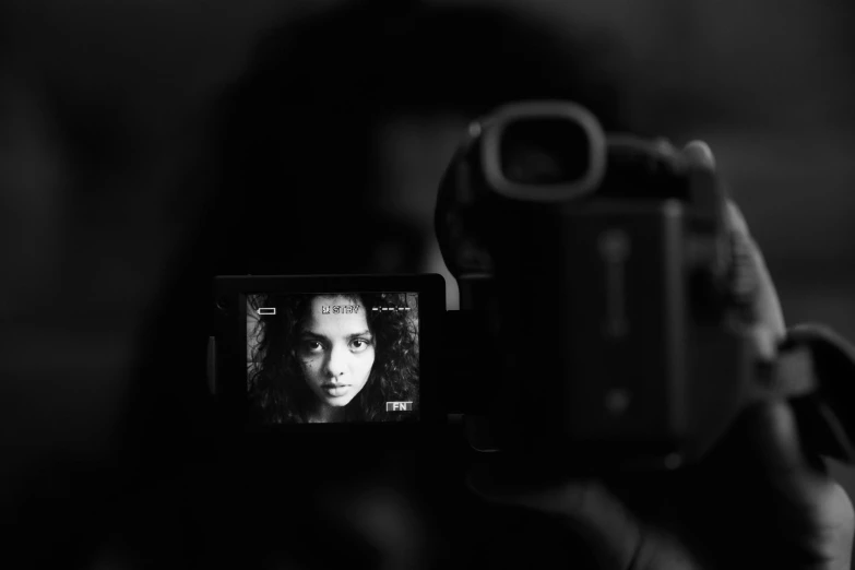a person taking a picture with a camera, a black and white photo, by Adam Marczyński, pexels contest winner, video art, imaan hammam, the eyes of sharbat gula, shot at dark with studio lights, portrait sophie mudd